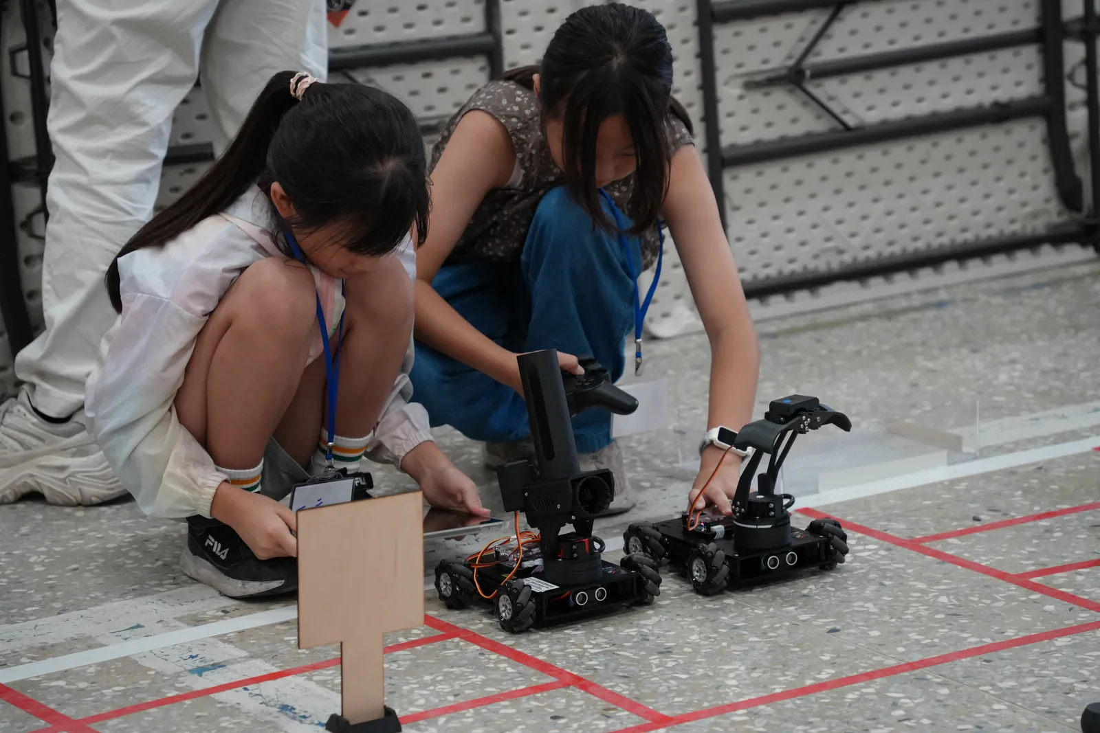 孩子蹲在賽道旁調整自走車
