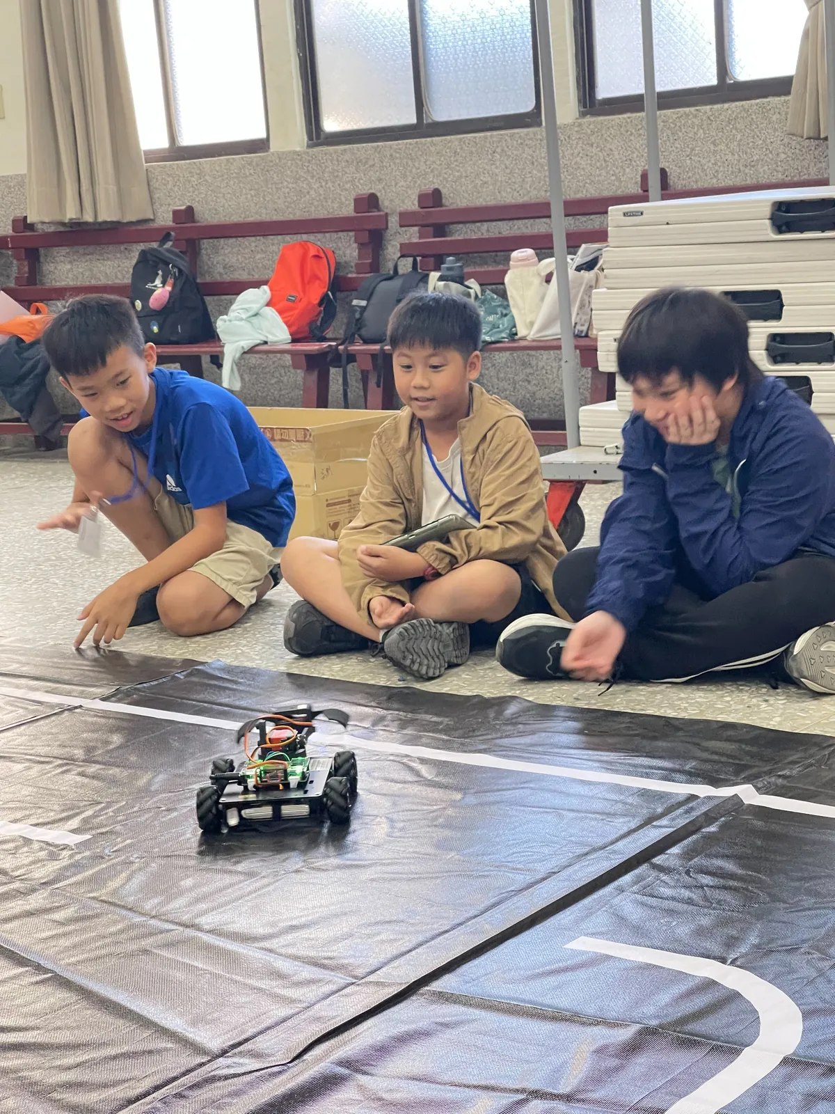 孩子圍在賽道旁觀察自走車